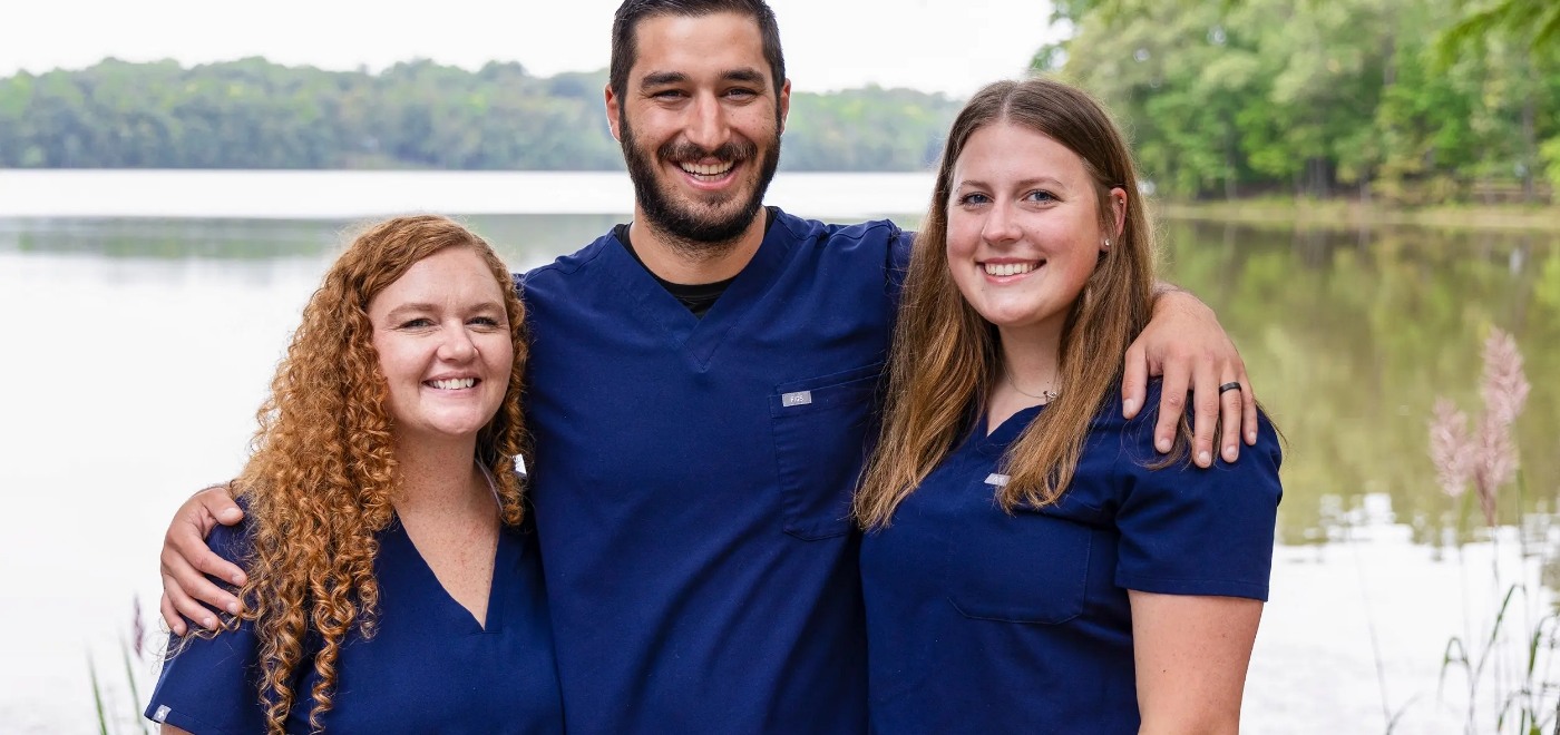Garner dentist smiling with each arm around a Samia Family Dentistry team member