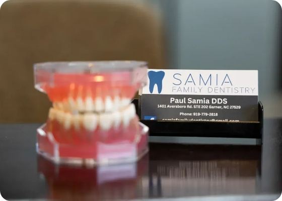 Model of teeth next to stack of business cards for Samia Family Dentistry