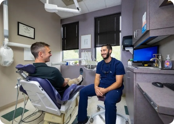 Man in dental chair smiling with his emergency dentist