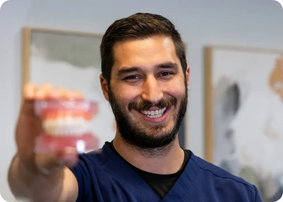 Doctor Samia smiling and holding a model of the teeth to the camera