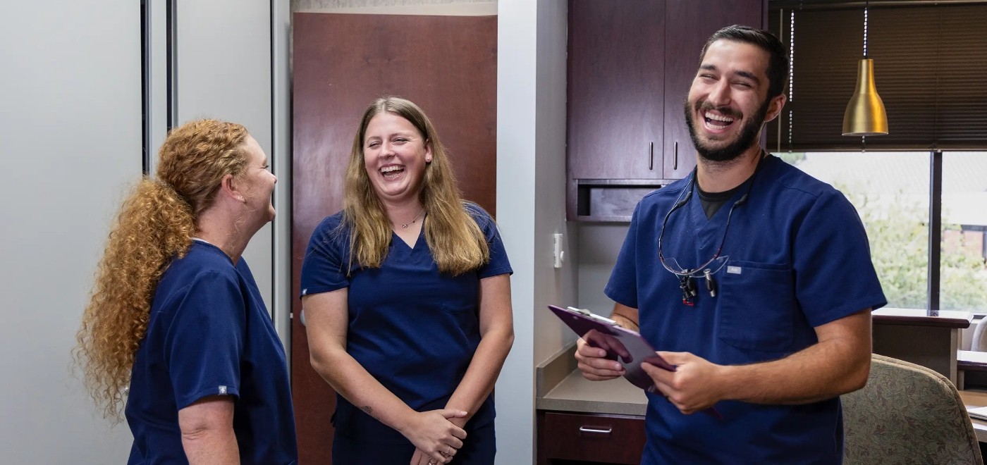 Dentist and two team members laughing at Garner dental office