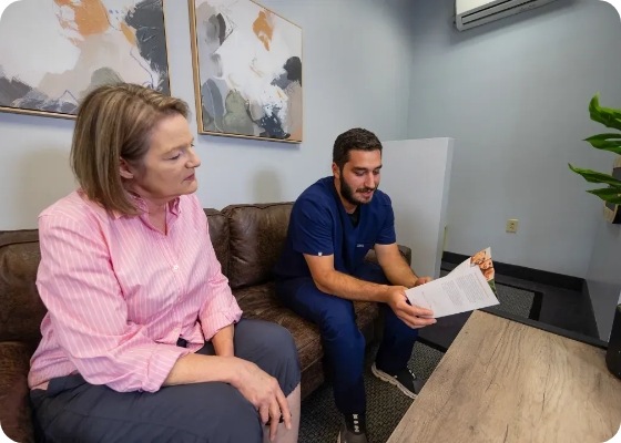 Doctor Samia sitting on couch and showing a paper to a patient
