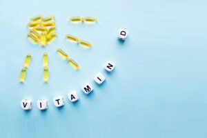 Vitamin D supplements arranged like sunbeams next to dice spelling "vitamin D"